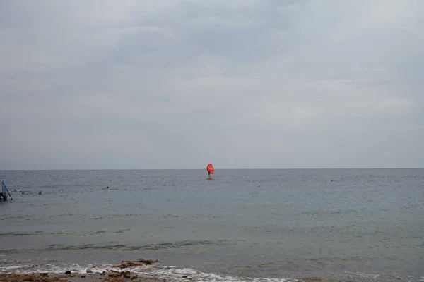 アカバ湾の紅海に赤い帆を持つウィンドサーファー ウィンドサーフィンはサーフィンとセーリングの組み合わせである水上スポーツです エジプト南シナイ県ダハブ — ストック写真