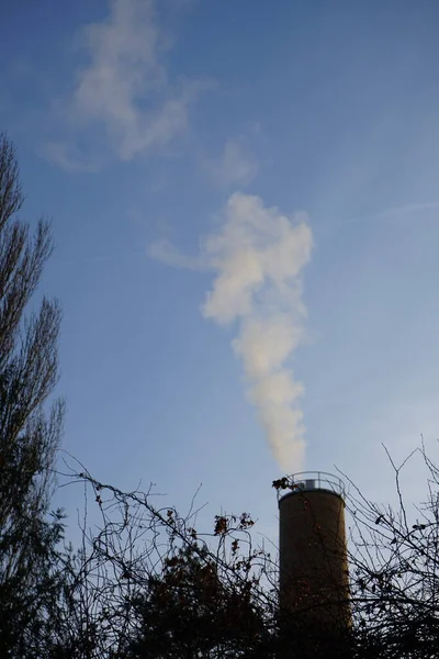 Smoke from a chimney from a boiler house against the sky at sunset in December. Berlin, Germany