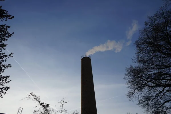 Smoke from a chimney from a boiler house against the sky at sunset in December. Berlin, Germany