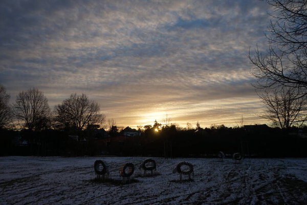 Decorative aluminum sheep on a snowy meadow at sunset in January. Berlin, Germany 