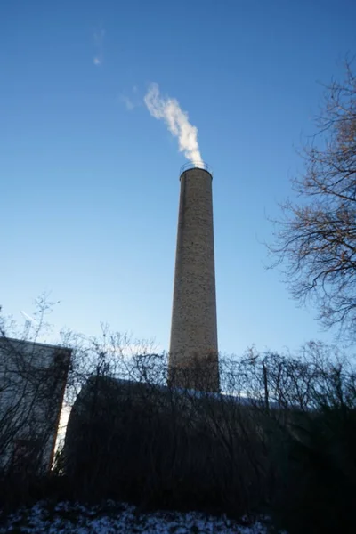 A smoking chimney from a boiler house against the sky in January. Berlin, Germany