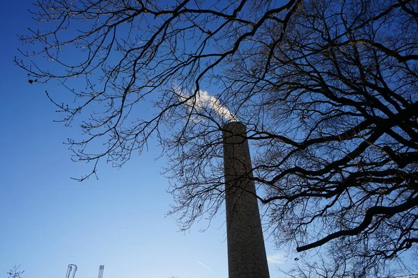 A smoking chimney from a boiler house against the sky in January. Berlin, Germany