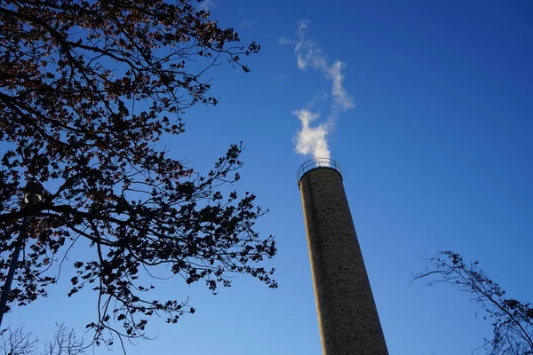 A smoking chimney from a boiler house against the sky in January. Berlin, Germany