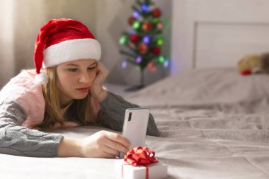 Noel çevrimiçi tebrikler. Video görüşmesi için telefon kullanan bir kadın..