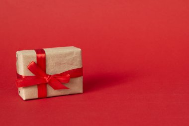 Kırmızı arka planda kırmızı kurdeleli hediye kutusu. Noel için hediye, yeni yıl, sevgililer günü, kopyalama alanı