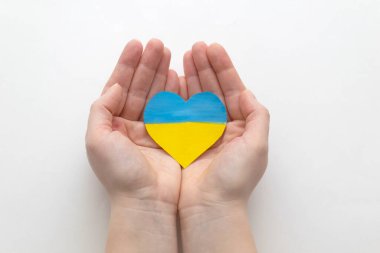Ukrayna 'daki savaşı bitirme kavramı. Ukrayna bayrağının renginde bir kalp Kadın ellerinde