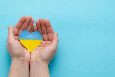 Ukrayna 'daki savaşı bitirme kavramı. Ukrayna bayrağının renginde bir kalp Kadın ellerinde
