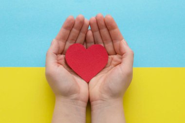 Ukrayna 'daki savaşı bitirme kavramı. Ukrayna bayrağının renginde bir kalp Kadın ellerinde