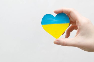 Ukrayna 'daki savaşı bitirme kavramı. Ukrayna bayrağının renginde bir kalp Kadın ellerinde