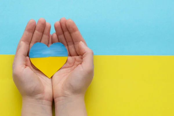 The concept of ending the war in Ukraine. heart in the colors of the flag of Ukraine in female hands