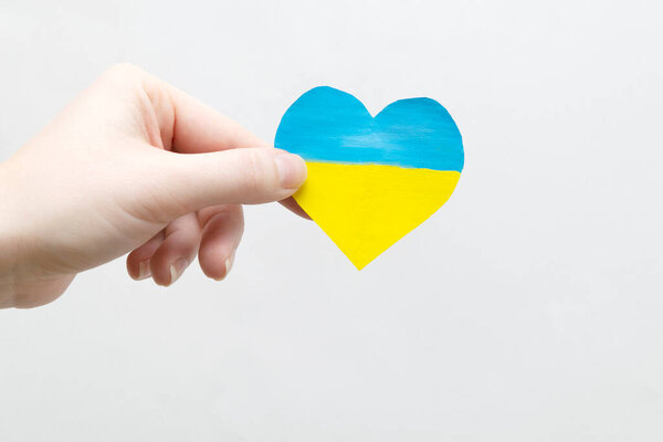 The concept of ending the war in Ukraine. heart in the colors of the flag of Ukraine in female hands