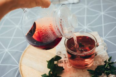 Bitki çayı çaydanlıktan bir fincana dökülür. Yataktaki ahşap tepside. Sıcak bir sonbahar. Yatak odasında kahvaltı. Üst görünüm.