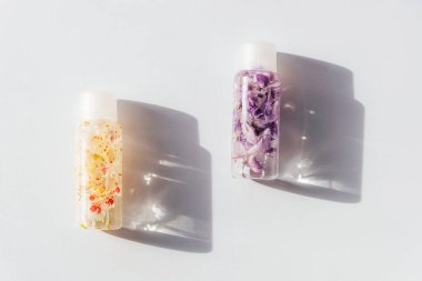 İçinde çiçek suyu olan iki kozmetik şişe mi yoksa güneş ışığında sert gölgeli tentür mü? Doğal kozmetik konsepti. Üst manzara, düz uzanma.