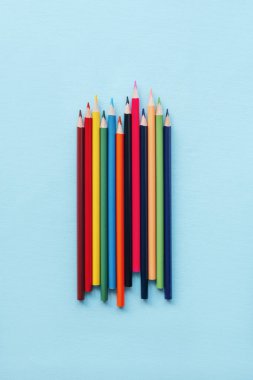 Mavi arka planda renkli kalemler. Okul malzemeleri. Üst manzara, düz uzanma.