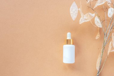 Bej arka planda beyaz serum şişesi ve ay çiçeği. Doğal kozmetik konsepti. Üst görünüm, düz görünüm, kopyalama alanı