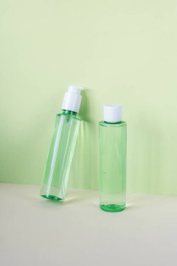 Yeşil arka planda yüz yıkama jeli ve tonik olan yeşil kozmetik şişeleri. Doğal organik kozmetik kavramı. Ön görünüm, modelle.
