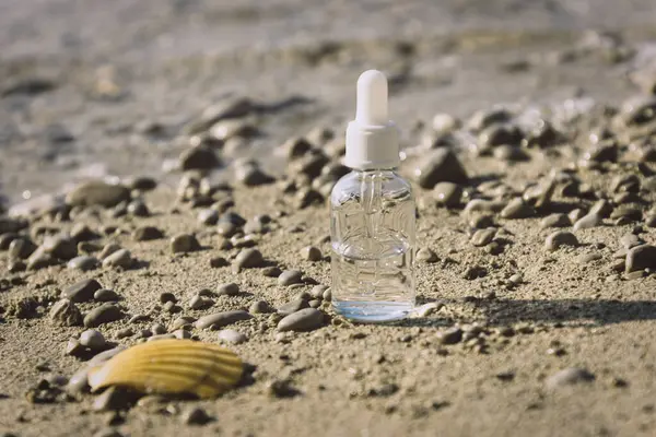 화장품 보습, 기름 혹은 혈청 병 이 조개 껍질 옆 해변 모래 속에 있다. 천연 화장품 여름 방학 컨셉트. 닫아 — 스톡 사진