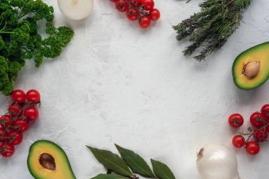Beyaz arka planda kiraz domatesleri, avokado, biberiye, soğan, defne yaprakları ve maydanoz. Üst görünüm, düz görünüm, kopyalama alanı