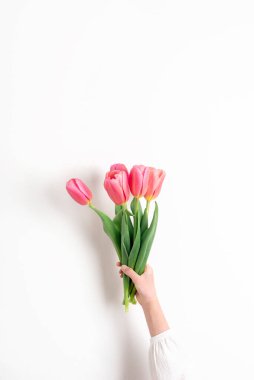 Beyaz arka planda güzel pembe lale çiçeklerinden oluşan buketi tutan kızlar.