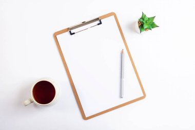 Beyaz masaüstü pano, bir fincan çay, kalem ve sulu bitki. Minimum düzlük, üst görünüm, modelleme.