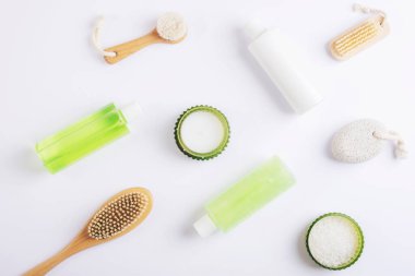 Beyaz zemin üzerinde kozmetik düz yatıyordu. Deniz tuzu, mum, yüz ve vücut fırçaları, sünger taşı, duş jeli ve vücut losyonu. Spa ve sağlık konsepti. Üst manzara, düz uzanma.