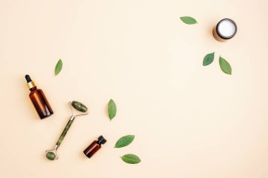 Kavanozda krema, serum şişesi ve yeşil yapraklı, yeşil arka planda yeşim bir yüz silindiri. Düz yat, boşluğu kopyala.