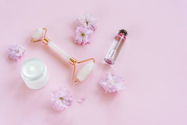 Sakura çiçekli doğal organik kaplıca seti. Yüz silindiri, kozmetik krem ve pembe arka planda çiçek suyu. Cilt bakımı, güzellik tedavi konsepti. Boşluğu kopyala