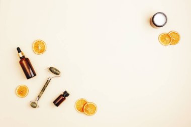 Kozmetik aksesuarlar, kurutulmuş portakal dilimleriyle doğal bej arka planda yaşlanmayı önleyen kozmetik güzellik malzemeleri. Üst görünüm, düz görünüm, kopyalama alanı.