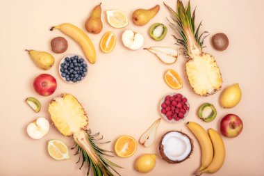 Bej arka planda çeşitli meyvelerin çerçevesi. Üst görünüm, düz görünüm, kopyalama alanı. Tropik meyveler, vejetaryen yiyecekler, sağlıklı beslenme.