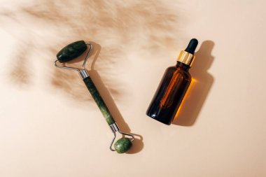 Yüz silindiri, açık bej arka planda selvi gölgesi olan serum şişesi. Doğal kozmetik, aromaterapi, güzellik tedavi konsepti. Üst manzara, düz uzanma.