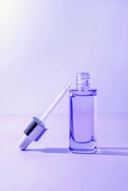 Mor arkaplanlı kozmetik serumu. Deri bakımı konsepti. Yakın çekim..