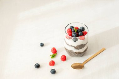 Beyaz masada taze ahududu ve yaban mersinli Chia pudingi, yakın plan..