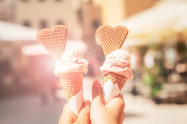 Tasty ice creams in hands. Blurred background of summer city cafe.