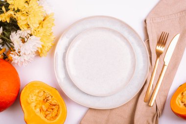 Stylish table setting, yellow dahlia flowers, pumpkins and plates on white table. Top view, flat lay, copy space.