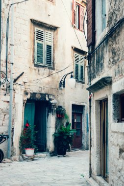 Narrow old street in Sibenik town with green door, windows and plants. Dalmatia, Croatia.
