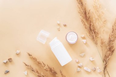 Organik doğal kozmetik ürünleri ve bej arka planda kuru otlar. Üst görünüm, düz görünüm, model.