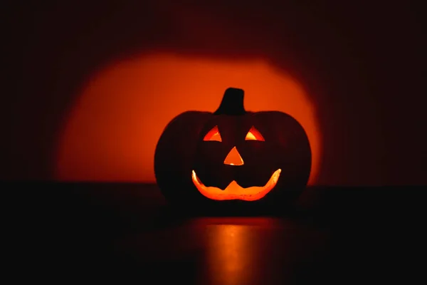 Jack-O-Lantern in the dark on orange background. Halloween concept.
