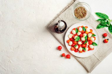 Çeri domatesli İtalyan caprese salatası, mozzarella, fesleğen, beyaz bir masada balzamik sos. Üst görünüm, düz görünüm, kopyalama alanı.