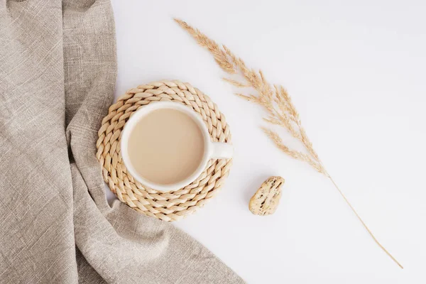 Coffee or cocoa cup, cloth napkin and pampas grass on white background. Still life. Top view, flat lay.