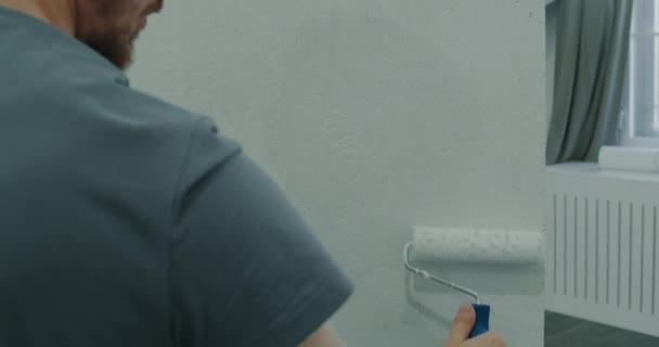 Bouw en reparatie. Een man schildert een muur met een roller. Een man repareert. Een man repareert de kamer. Modern interieur in het huis. Reparatie — Stockvideo