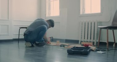 Adam evinde tadilat yaparak mobilya yapıyor. Usta tamirci mobilya montajında çalışıyor.
