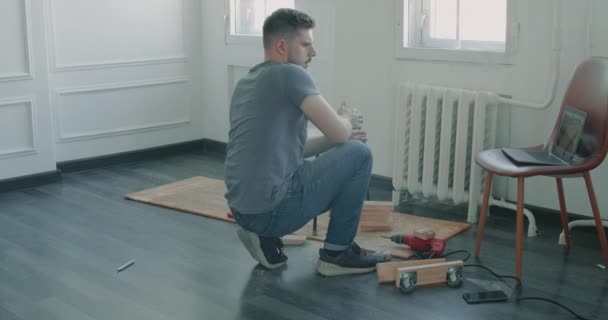 Человек сам строит мебель, делая ремонт дома. Мастер-ремонтник работает над сборкой мебели — стоковое видео