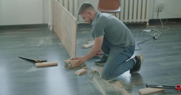 Man is building furniture himself making renovation at home. Master repairman is working assembling furniture — Stock Video