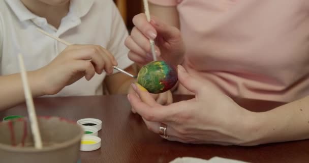 Mutter und Sohn bemalen ein Ei. Vorbereitungen für die Osterferien — Stockvideo