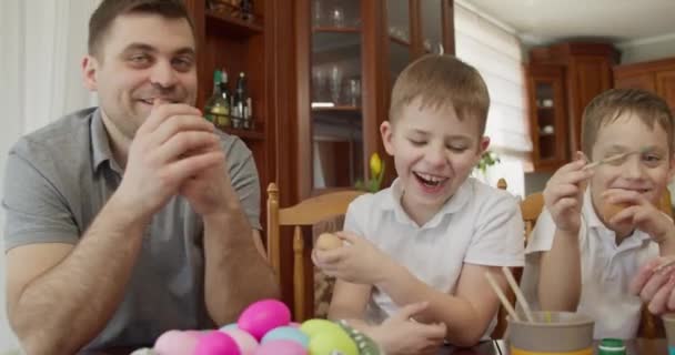 El padre con dos hijos pinta los huevos de Pascua. preparativos para las vacaciones de Pascua — Vídeos de Stock