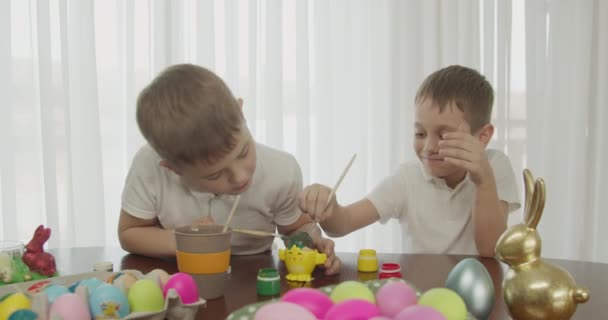 Twee kinderen schilderen een paaseieren met een borstel — Stockvideo