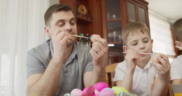 Papa en zijn zoon schilderen paaseieren. — Stockvideo