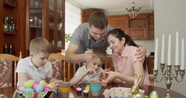 Paassfeer. De familie schildert paaseieren. Papa maakt zijn moeders gezicht vuil met een borstel. — Stockvideo