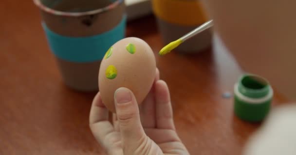 Macro, tangan dingin memegang telur ayam dan mulai melukisnya. Bersiap untuk Paskah. Kreativitas anak-anak, kerajinan. Kelas utama pada pewarnaan telur. Tampilan atas — Stok Video