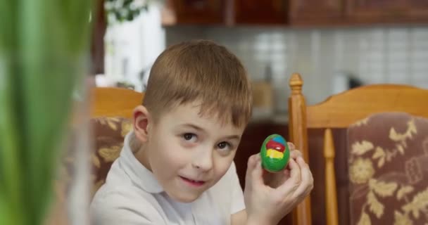 Chłopiec ma kolorowe jajko w kolorze zielonym, żółtym — Wideo stockowe